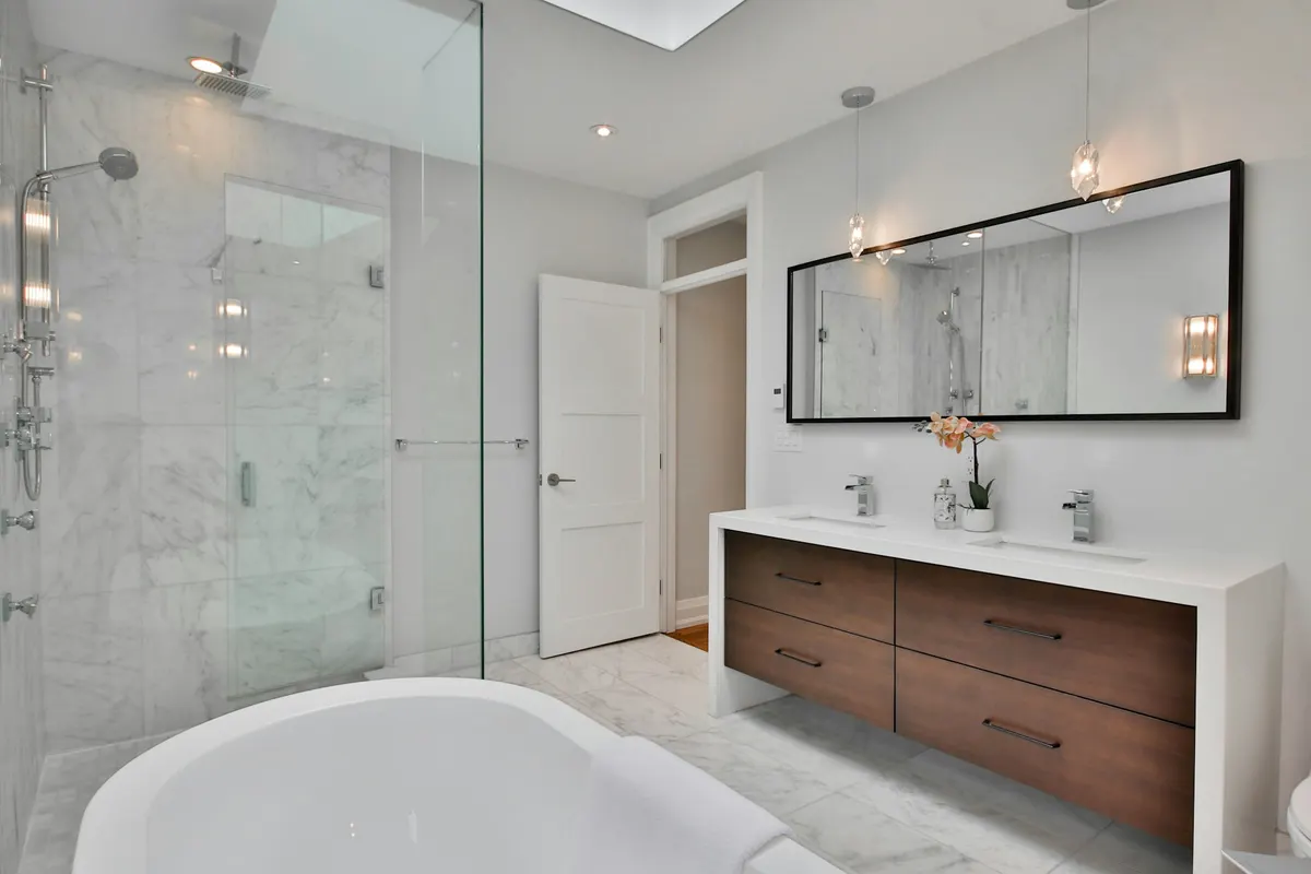 Full remodel with marble walls, a walnut double vanity, and a glass shower